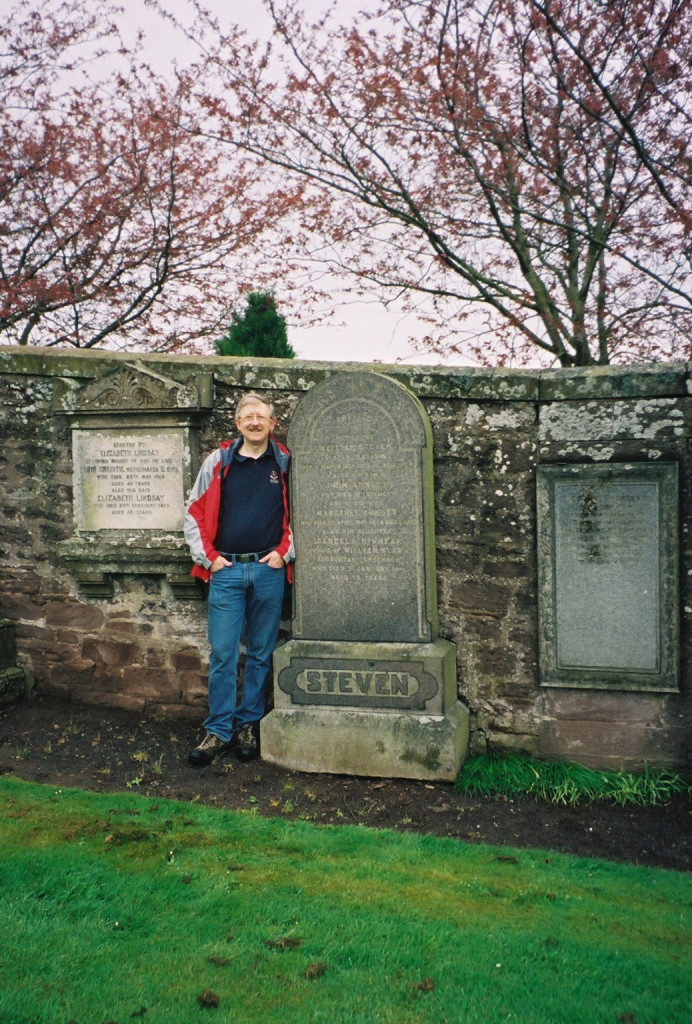 Man standing beside tombstone of some ancestors.