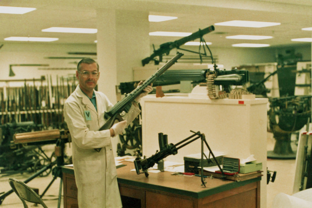 Barry Gillis at CWM arms vault 1985-08-29 - Holding Charlton automatic rifle conversion. Invented by a New Zealander, this appears to be an Australian made variant. An Italian Villa-Perosa sub-machine gun in on the desk. This was the World's FIRST SMG.