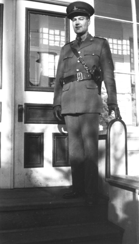 Police officer standing on front porch of a building. Constable Ted Brue, BC Provincial Police