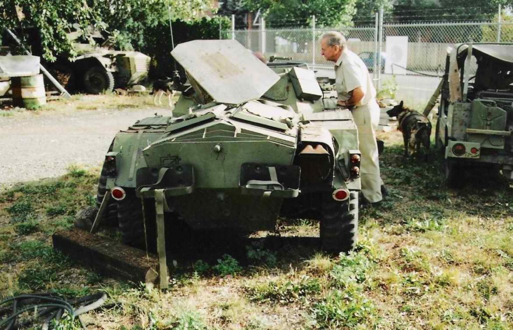 Man leaning on Ferret Scout Car and looking into it.