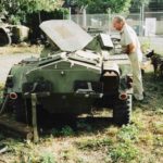 Man leaning on Ferret Scout Car and looking into it.