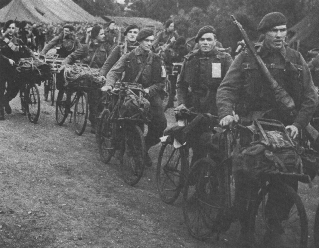 Royal Marine Commandos in Southern England immediately before D-Day, June 1944. They have BSA Airborne Bicycles with the Everest Carrier fitted to the front. They have finished their kit inspection, so the loaded rucksacks, rope, ammunition etc. are now loaded onto the bicycles as they head off to be loaded onto landing craft/ships.