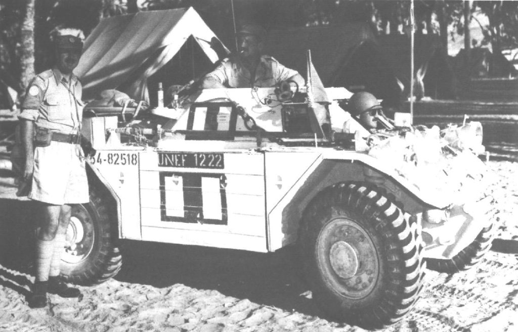 Man standing beside a white painted Ferret Scougt Carn and another man inside it.