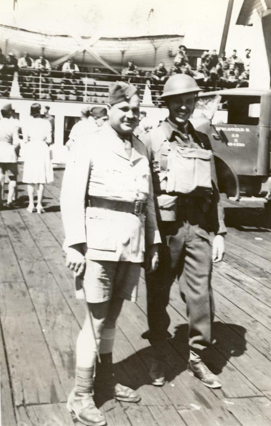 Two officers standing in uniform on the dock. Army ttruck behind them Officer on right with helmet and respirator (gas mask) etc. On the dock at Nanaimo. With the Lincoln and Welland Regiment on the dock at Nanaimo, British Columbia circa 1942 - Lieutenant A. H. Stevens on the right. 