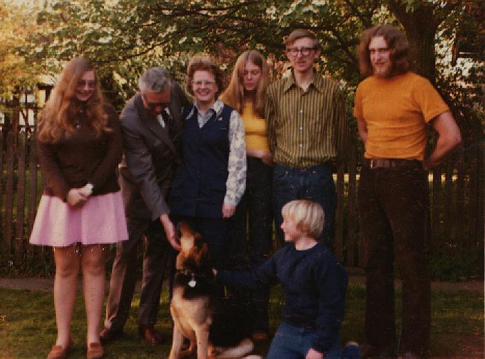 Family group of mother, father, 5 kids and dog in backyard of house in Vancouver, BC. The whole Stevens family as we were about 1973 in the backyard of our house on Osler Street in Vancouver. Rob is in front with the German Shepherd and is about 10 years old in this photo