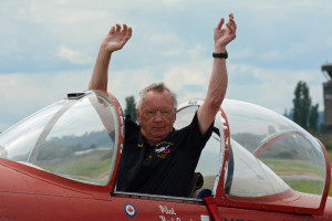 Pilot on waving to crowd with both hands while his aircraft is taxiing.