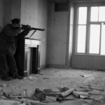 1945-04-07 Arthur Godin, a sniper with Le Regiment de la Chaudiere, Canadian Army at Zutphen, Netherlands. Notice that he is staying back in the room so that the enemy would have a difficult time spotting him. (L&AC MIKAN 3524681)