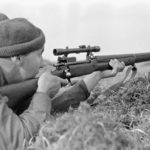 Sniper aiming his rifle. 1942-04-12 to 26. Canadian sniper in Assault landing course England P-14. Photo by Sgt. Al W. Grayston. (L&AC PA-213632 MIKAN 3599772)