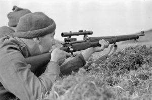 Sniper aiming his rifle. 1942-04-12 to 26. Canadian sniper in Assault landing course England P-14. Photo by Sgt. Al W. Grayston. (L&AC PA-213632 MIKAN 3599772)