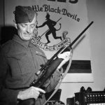 Soldier holding a sniper rifle in an office. 1942-07-30 An unidentified Corporal of the Royal Winnipeg Rifles holding a Ross sniper rifle with a Winchester A5 scope in Ottawa, Ontario. (L&AC PA-208603 MIKAN 3589887)