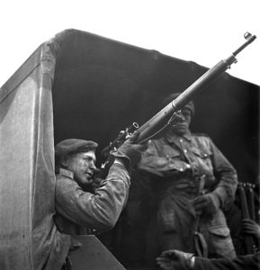 1943-04-23 Unidentified soldier sighting with his telescope equipped P-14 sniper rifle while sitting in the back of a 15 Cwt truck. 2 Canadian Infantry Division Sniper Training, England. Photo by Lieut. Grederick G. Whitcombe (L&AC PA-211643 MIKAN 3596210)