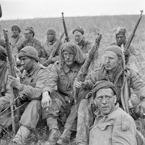 Soliders with rifles sitting on hillside on a smoke break. 1943-04-24 2 Canadian Infantry Division Sniper training England. Photo by Lieut. Dwight E. Dolan (L&AC PA-177141 MIKAN 3260082)