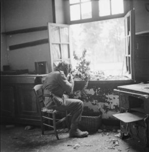 1944. British-sniper-Private Sutcliffe seated at a window in or near Caen, France. Caen is a major city just inland from the D-Day invasion beaches.