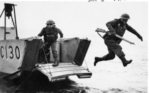 Brtiish soldier leaping off of a landing craft carrying his rifle.