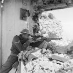 Sniper aiming his rifle from a damaged building.