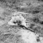 Sniper camougflaged and prone with rifle.