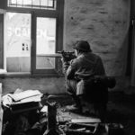 British sniper aiming out of a window.