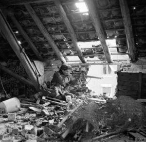 Sniper in attic British. "C" Company 5 Battalion, Black Watch 51 Highland Division, Gennep Netherlands . Posed photo as position is unsafe. By 5 AF&PU © IWM (B 14628)