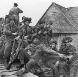 Canadian paratroopers riding on a British armoured vehicle.