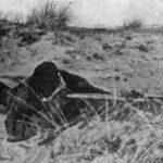 Sniper observing with a Scout Regiment Telescope among the sand dues on the German island of Sylt at a British Army sniping school.