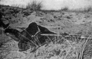 Sniper observing with a Scout Regiment Telescope among the sand dues on the German island of Sylt at a British Army sniping school.