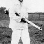 British sniper wearing a white snow suit and carrying his sniper rifle.