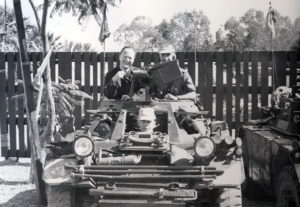 Front view of a Ferret Scout Car with three men in it.