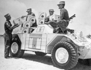 Soldiers in Ferret UNEF1209 saluting with beer bottles. (RCD Archives)