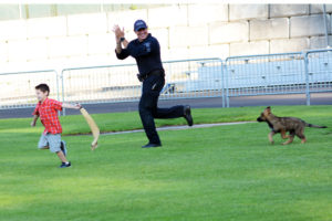 Police dog handler with puppy police dog and young boy with a drag for the puppy to grab. with his teeth. (D7100a 014)