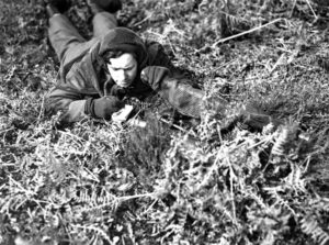 Canadian sniper making notes after observing during training in England.