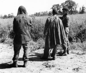 Three soldiers talking about a mission. They are standing and facing away from the camera.