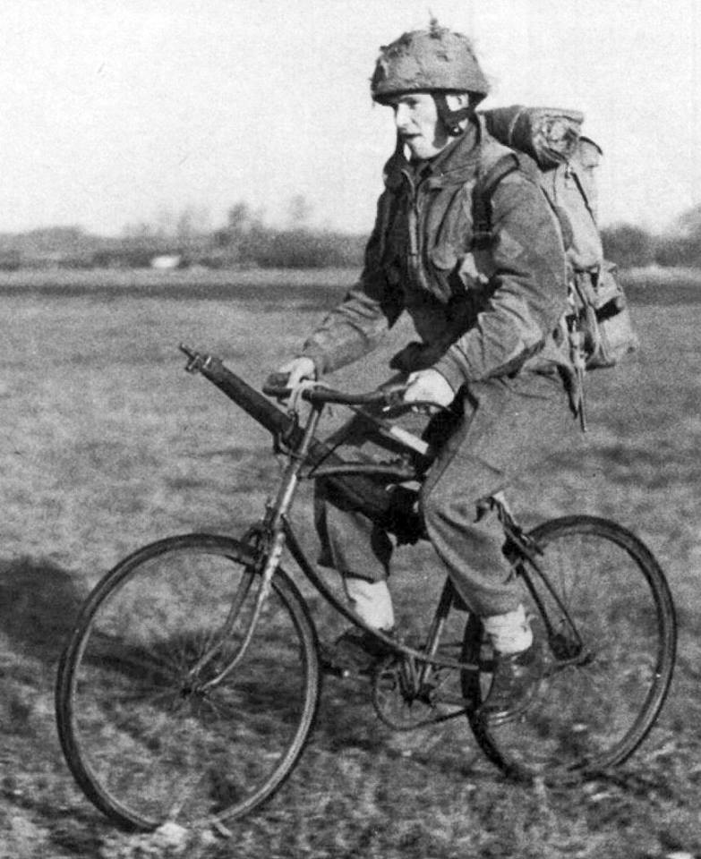 British airborne soldier riding a BSA airborne bicycle. There are no clips for the rfle, he is just using the sling looped over the handlebar and seat post. 