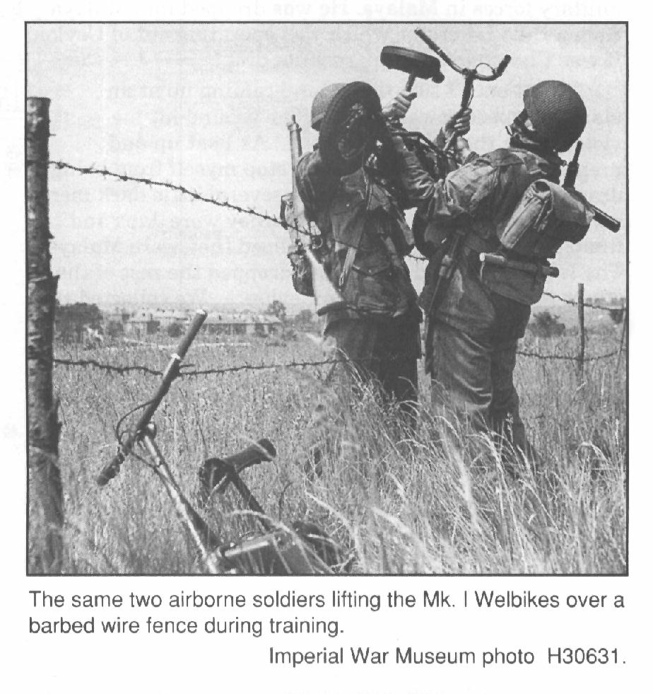 Airborne soldiers in training, lifting a Welbike over a fence. Man on right is wearing the now rare Sten Gun bayonet for the Mk. II.