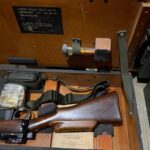 L42A1 - Right section in transit chest. Showing rifle and sling, Scope case strap NOS in packaging, cleaning lit, rifle and cling, and very rare bottle with lens brush.