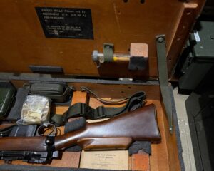 L42A1 - Right section in transit chest. Showing rifle and sling, Scope case strap NOS in packaging, cleaning lit, rifle and cling, and very rare bottle with lens brush.