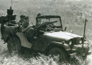 1977 - M38A1 CDN 2 or CDN3 Jeep. Sgt Dave Holwill as Commander (front passenger seat); Trooper Rob Bale as Observer in rear with C42 radio; Trooper Steve McCritchie as Driver. Reflective CANADA licence plate is covered but headlights are not. 1977 - M38A1 CDN 2 or CDN3 Jeep. Sgt Dave Holwill as Commander (front passenger seat); Trooper Rob Bale as Observer in rear with C42 radio; Trooper Steve McCritchie as Driver. Reflective CANADA licence plate is covered but headlights are not.